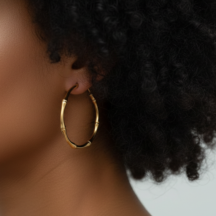 Gold bamboo hoop earrings worn by a brown-skinned model with 3C curly hair