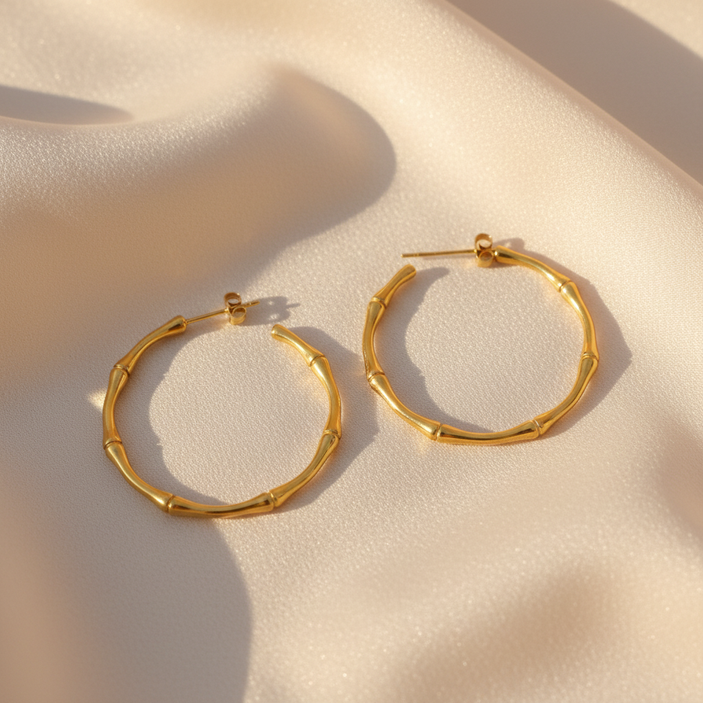 Gold bamboo hoop earrings styled on cream silk fabric